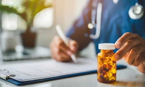hand-writing-prescription-with-pill-bottle-focus-against-clean-wall-backdrop